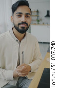 Engaging Conversation: A Thoughtful Individual in a Modern Workspace Expressing Ideas Through Gestures while Seated at a Table. Стоковое AI-видео, аниматор Владимир Федоров / Фотобанк Лори