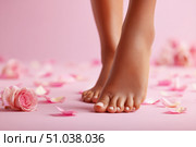 Woman's beautiful bare feet against a pink background. The soles and well-groomed toes and rose petals scattered around. Perfect skin tone. Pastel-colored backdrop for beauty and skin care advertising. Стоковое AI-изображение, AI-художник Марина Демидюк / Фотобанк Лори