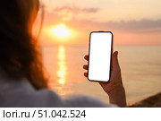 Girl with phone on the beach. Phone with blank white display in hand. Tourist with phone at sunset. Стоковое фото, фотограф Никита Бурденков / Фотобанк Лори