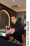 Professional bartender in black apron pours drink from shaker into glass.Male bartender pouring alcohol in glass, A young bartender making luxury cocktail. Редакционное видео, видеограф Zita Khasanova / Фотобанк Лори