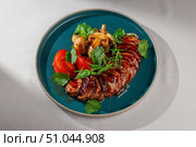 Sliced glazed duck breast served with grilled mushrooms, fresh tomatoes, cilantro and green onions on a rustic blue ceramic plate, Korean fusion presentation. Стоковое фото, фотограф Aleksandr Gavrilychev / Фотобанк Лори