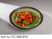 Spicy Korean chicken dish with red pepper, zucchini, onion, sesame seeds and cilantro served on a textured green ceramic plate with rustic glaze. Стоковое фото, фотограф Aleksandr Gavrilychev / Фотобанк Лори