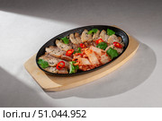 Sliced pork belly served on cast iron plate with traditional Korean kimchi, fresh cilantro, black sesame seeds and red chili peppers for garnish. Стоковое фото, фотограф Aleksandr Gavrilychev / Фотобанк Лори
