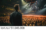 A man stands confidently in front of a lively crowd at a concert, addressing the audience with passion and energy. Стоковое AI-видео, аниматор Данила Большаков / Фотобанк Лори