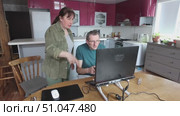 Using laptop on stand with connected game controller, man focuses on screen while woman gestures and speaks beside him. Стоковое видео, видеограф Владимир Григорьев / Фотобанк Лори