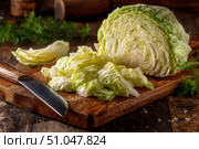 Organic freshly white cabbage on rustic table surface. Green fresh cabbage. Partially sliced raw shredded cabbage and a half on a wooden cutting board with a knife. Preparation of vegetables salad. Стоковое AI-изображение, AI-художник Марина Демидюк / Фотобанк Лори