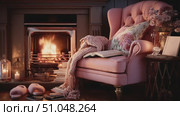 Cozy reading nook by the fireplace with a plush pink armchair, warm blanket, and soft ambiance in a home setting. Стоковое AI-видео, аниматор Ekaterina Ismagilova / Фотобанк Лори