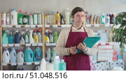 Adult man seller with folder conducting inventory in household chemicals store. Стоковое видео, видеограф Яков Филимонов / Фотобанк Лори