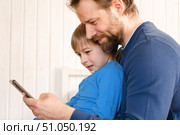 Father and son little boy laughing and using phone. They watching funny videos together, playing games on smartphone. Concept technology, smart phone addicted. Fun weekend activity. Modern fatherhood. Стоковое фото, фотограф Марина Демидюк / Фотобанк Лори