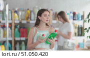 Woman went to the supermarket in the summer and chooses dishwashing detergent, she looks at the composition and environmental friendliness of the products. Visitors choose household chemicals in the store. Стоковое видео, видеограф Яков Филимонов / Фотобанк Лори