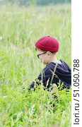 A boy with glasses and hearing aids in a red cap got lost in the forest and is picking berries in a clearing. Стоковое видео, видеограф Кашапова Эльвира / Фотобанк Лори