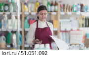 Trainee saleswoman reacts emotionally to the paperwork, she is irritated and dissatisfied. Woman experiences burnout at work. Salesperson works with papers in the warehouse of a household compartment of a supermarket. Стоковое видео, видеограф Яков Филимонов / Фотобанк Лори