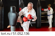 Aged man in white gi practicing strikes on dummy in dojo. Стоковое фото, фотограф Яков Филимонов / Фотобанк Лори