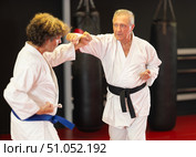 Older karate fighter practicing paired kumite in dojo. Стоковое фото, фотограф Яков Филимонов / Фотобанк Лори