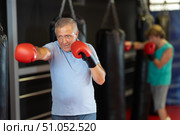 Senior man training punches on heavy bag in gym. Стоковое фото, фотограф Яков Филимонов / Фотобанк Лори