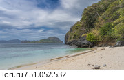 Beautiful secluded sandy tropical beach. Without people. Turquoise ocean. Picturesque boulders by the water. Tropical vegetation on the hill. Mountains in the distance. Blue sky, clouds. Philippines. Стоковое фото, фотограф Вера Ивановна Кубарева / Фотобанк Лори