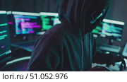 A hooded figure focuses intently on multiple computer screens displaying lines of code in a dimly lit and modern workspace, symbolizing the world of programming and hacking. Стоковое AI-видео, аниматор Владимир Федоров / Фотобанк Лори