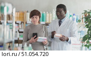 Woman in pharmacy scans QR code on pills, studies item in detail, collects information online, uses quick link to access drugs instructions. African man pharmacist offer available assortment items. Стоковое видео, видеограф Яков Филимонов / Фотобанк Лори