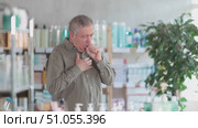 Elderly man struggling with strong coughing and chest pain while standing in pharmacy, seeking medication for cold, flu, or bronchitis symptoms. Стоковое видео, видеограф Яков Филимонов / Фотобанк Лори