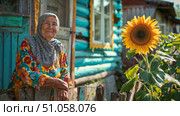 Бабушка в платке и цветастом платье у своего деревенского дома. Grandmother wearing a headscarf and a colorful dress outside her village house. Стоковое AI-изображение, AI-художник Смирнова Светлана / Фотобанк Лори