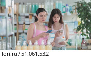 Portrait of friendly family of mother and daughter customers holding, scan QR code on label and selecting cream or skin care product in modern drugstore. Стоковое видео, видеограф Яков Филимонов / Фотобанк Лори