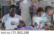 Multiethnic group of engaged fashion students of different ages sewing together, cutting fabric, and adjusting garment on mannequin, enjoying teamwork during hands-on dressmaking class. Стоковое видео, видеограф Яков Филимонов / Фотобанк Лори