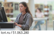 Young woman student working or studying at computer in library. Стоковое видео, видеограф Яков Филимонов / Фотобанк Лори
