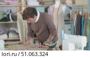 Qualified clothing designer draws a sketch on paper in a sewing workshop. Стоковое видео, видеограф Яков Филимонов / Фотобанк Лори