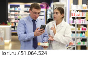 Girl pharmacist talk to man buyer and help to scan QR code on package , find out missing information about medical cosmetics. Specialist in pharmacy answer buyers question, provide consulting services. Стоковое видео, видеограф Яков Филимонов / Фотобанк Лори