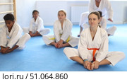 Group of multinational children in white kimono sits in a butterfly pose and practices stretching in sport gym. Стоковое видео, видеограф Яков Филимонов / Фотобанк Лори