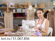 Positive young female dressmaker working with sewing-machine. Стоковое фото, фотограф Яков Филимонов / Фотобанк Лори