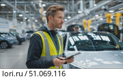 Worker inspects vehicles and takes notes in busy automotive production facility. Стоковое AI-видео, аниматор Сергей Толмачёв / Фотобанк Лори