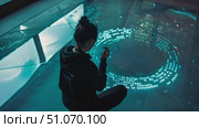 A woman engages with a cutting-edge digital display, manipulating swirling patterns of light and text with her hands. Стоковое AI-видео, аниматор Данила Большаков / Фотобанк Лори