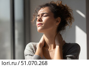 Красивая молодая девушка, держащаяся руками за шею от боли, стоит в ярком современном интерьере. Стоковое AI-изображение, AI-художник Максим Коломыченко / Фотобанк Лори