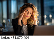 Красивая молодая бизнесвумен с головной болью сидит в современном офисе за письменным столом с ноутбуком. Стоковое AI-изображение, AI-художник Максим Коломыченко / Фотобанк Лори