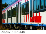 An MCD train with red and white stripes is moving along the rails in a suburban area. Russia. Moscow oblast. 14.08. 2025. Редакционное фото, фотограф Ярославский Максим / Фотобанк Лори