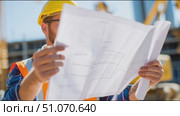 Construction worker reviews building plans at job site during sunny afternoon. Стоковое AI-видео, аниматор Сергей Толмачёв / Фотобанк Лори