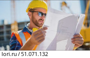 Construction worker reviewing plans on a sunny day at the building site in the city. Стоковое AI-видео, аниматор Сергей Толмачёв / Фотобанк Лори