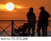 Семейная пара с ребёнком на фоне закатного солнца. Редакционное фото, фотограф Владимир Белоусов / Фотобанк Лори