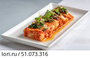 Kimchi fermented napa cabbage with herbs and sesame seeds on white plate. Стоковое AI-изображение, AI-художник Юрий Поздников / Фотобанк Лори