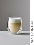 Latte macchiato coffee in double walled thermo glass on white table. Стоковое AI-изображение, AI-художник Юрий Поздников / Фотобанк Лори