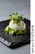 Egg shaped dessert with green cream and microgreens on black slate plate. Стоковое AI-изображение, AI-художник Юрий Поздников / Фотобанк Лори