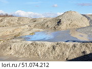 A mud volcano and a stream of grey clay from an eruption and gas escape. Cracked soil surface. Texture of a mudflow. Стоковое фото, фотограф Наталия Кирсанова / Фотобанк Лори
