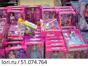 A shop window with bright pink packaging for dolls from various brands, including Abbie, Calleigh and Defa Lucy. The toys are presented in various outfits - evening dresses, ball gowns, accessories. In the center is a set of miniature horses in a transparent bag. The dolls are in neat boxes with a transparent window, allowing you to see their appearance. In the background are store shelves with other toys, creating an atmosphere of children's assortment. (2015 год). Редакционное фото, фотограф Анна Кривицкая / Фотобанк Лори