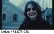 A spooky character with dark makeup and red lips strolls through the deserted streets as dusk falls. Стоковое AI-видео, аниматор Данила Большаков / Фотобанк Лори