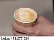 Close-up of a paper cup in a man's hand with coffee, cappuccino with a foam pattern. Стоковое фото, фотограф Наталья Угрюмова / Фотобанк Лори