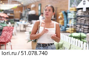 Smiling casual young girl looking with interest for functional furniture and accessories in modern garden store. Стоковое видео, видеограф Яков Филимонов / Фотобанк Лори