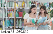 Happy mom and daughter in summer clothes choosing shampoo in large store. Стоковое видео, видеограф Яков Филимонов / Фотобанк Лори