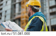 Construction worker reviews project plans at building site in urban area with crane in background. Стоковое AI-видео, аниматор Сергей Толмачёв / Фотобанк Лори