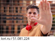 Serious young man with headphones making a stop gesture with his hand outdoors. Стоковое фото, фотограф Raquel Corcoles Mendez / Фотобанк Лори